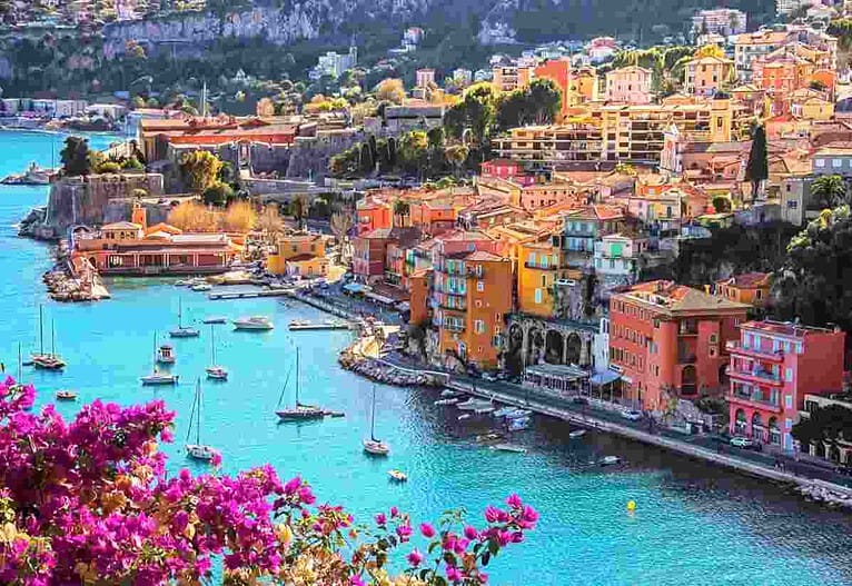 Pamje panoramike e Côte d’Azur me bregdetin mesdhetar, ndërtesa shumëngjyrëshe dhe detin e kaltër në Rivierën Franceze.