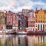 Pamje e shtëpive tradicionale shumëngjyrëshe përgjatë kanaleve të Amsterdamit, Holandë.