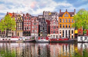 Pamje e shtëpive tradicionale shumëngjyrëshe përgjatë kanaleve të Amsterdamit, Holandë.