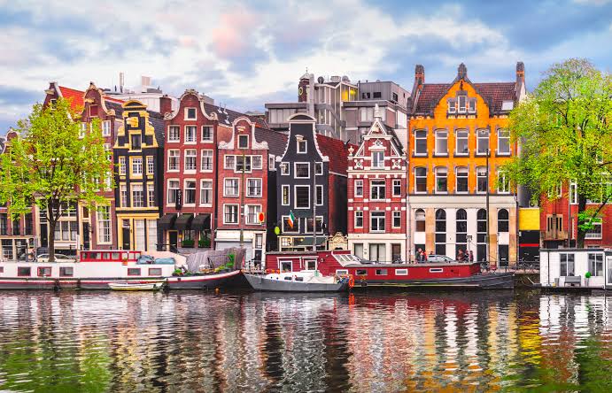 Pamje e shtëpive tradicionale shumëngjyrëshe përgjatë kanaleve të Amsterdamit, Holandë.